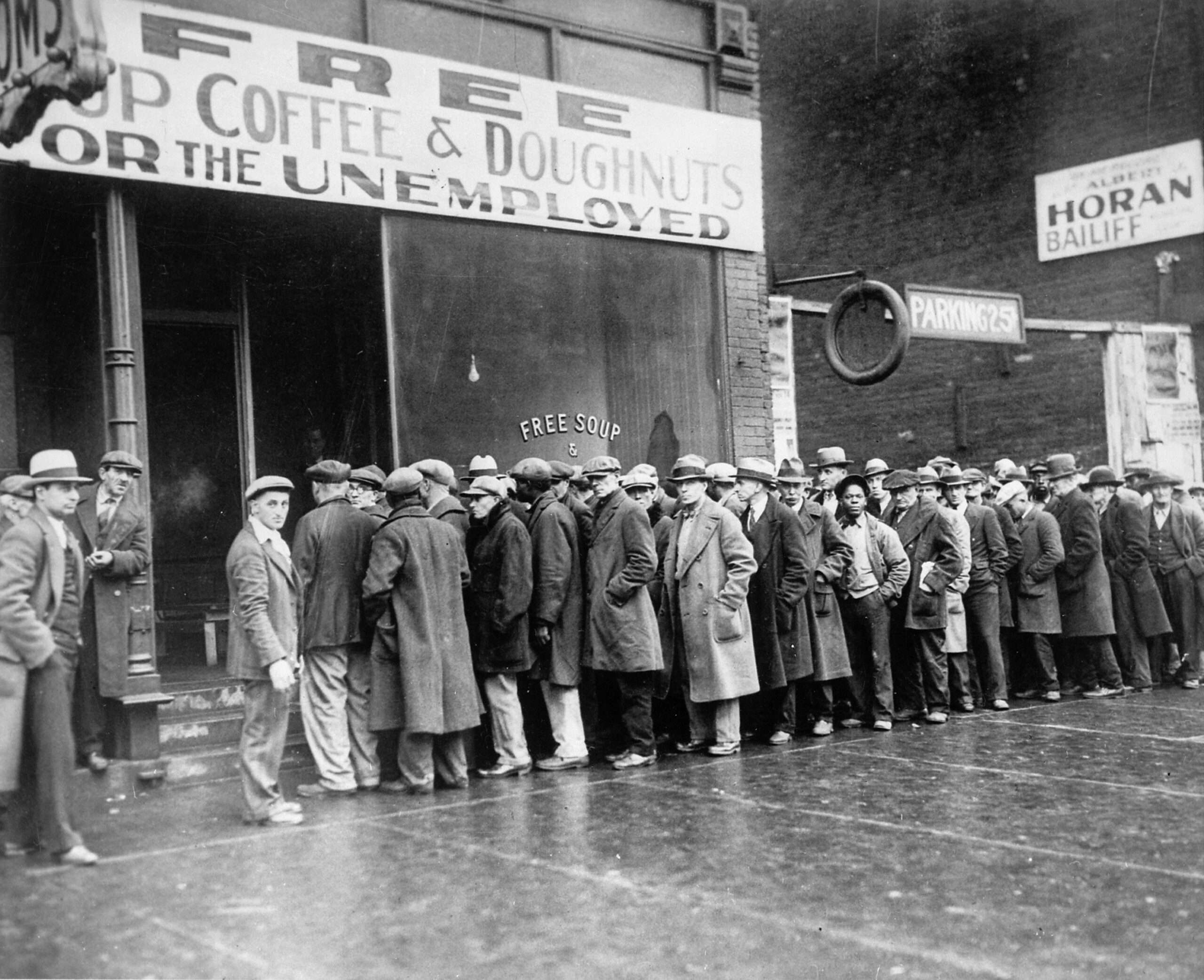 Black and white photo of men standing in line waiting for food during the Great Depression.